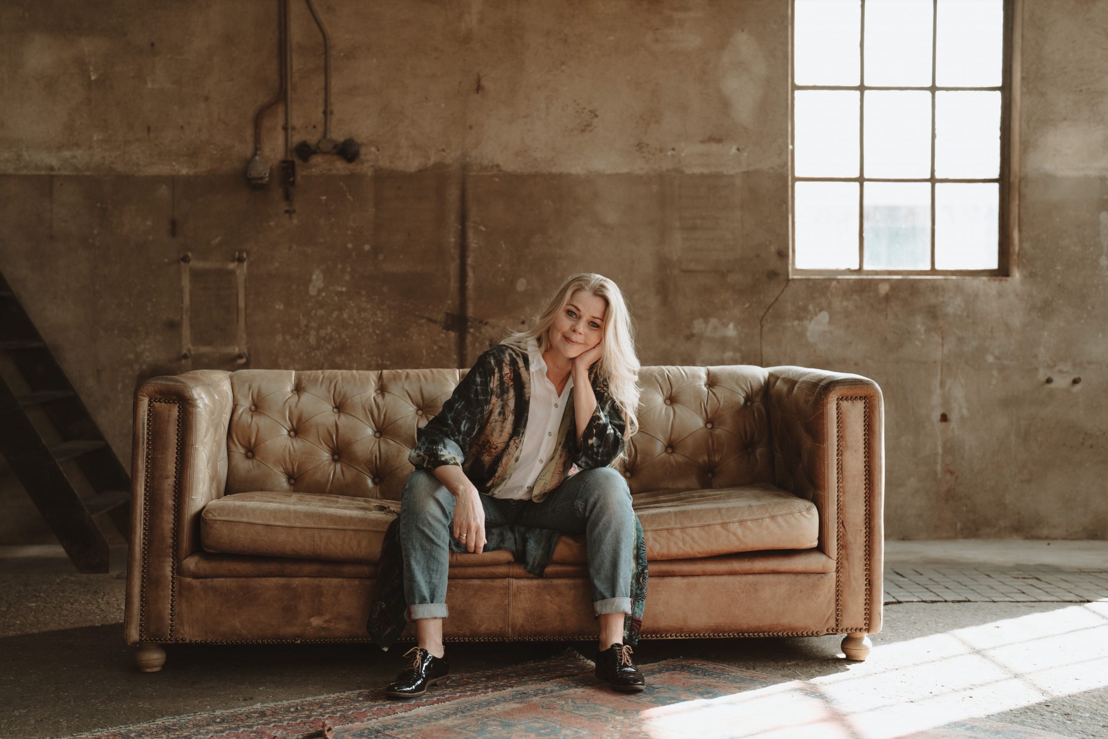 Annemieke op een leren bank in een oude fabriekshal